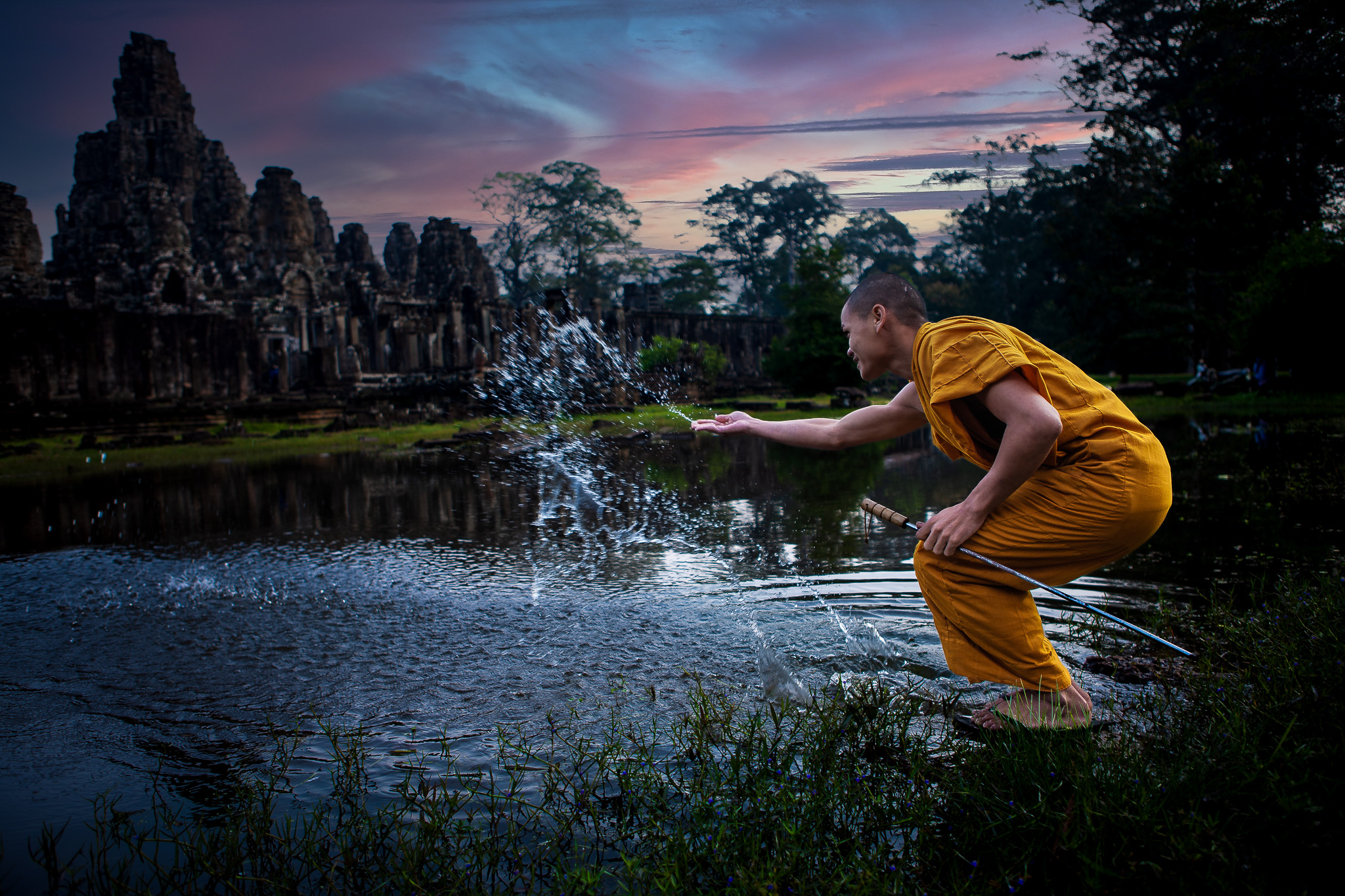 Discover the enchanting world of Angkor Wat, where ancient ruins and spiritual traditions converge in a captivating dusk ritual. Immerse yourself in the timeless beauty of this UNESCO World Heritage site, as a saffron-robed monk gracefully throws water from a moat, symbolizing purification and spiritual cleansing. This reprocessed photo transports you to a bygone era, evoking a sense of awe and reverence for the Khmer civilization. Explore the intricately carved temples, towering spires, and mystical aura that make Angkor Wat a must-visit destination. Experience the magic of Southeast Asia's cultural heritage as you witness this mesmerizing sunset scene and delve into the rich tapestry of religious practices. Angkor Wat awaits, ready to ignite your senses and leave an indelible imprint on your soul.